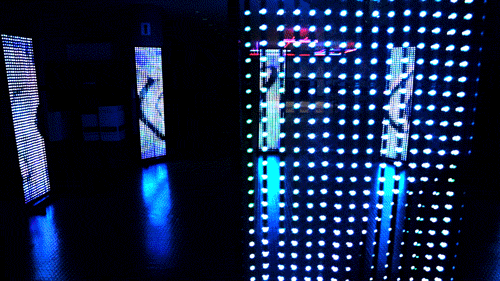 alt="8 LED screens in a circle displaying blue abstract content"